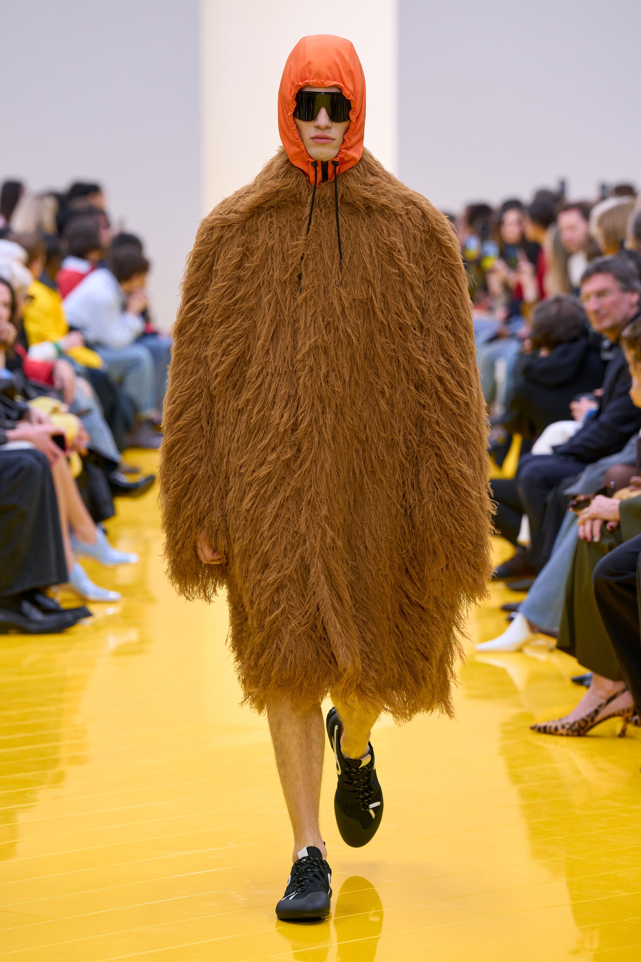 Jonathan Anderson 为 Loewe 带来一场充满艺术实验的秀：黄色地面与鲜明色彩形成强烈视觉舞台，极简廓形针织、雕塑化皮革外套、夸张毛绒结构和实验比例裙装共同构建一种“可穿戴雕塑”。从鲜黄、亮蓝到浓郁棕色毛绒，材质对比成为本季核心语言，既有幽默感也带有博物馆式艺术气质-顽石频道趋势研究